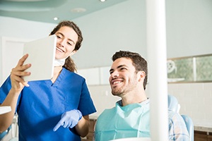 Dentist and patient smiling while reviewing paperwork