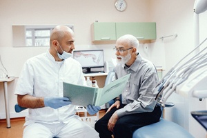 older man talking to dentist about a denture
