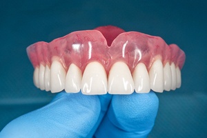 close-up of gloved hand holding upper denture in Waterford