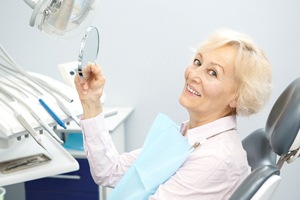 Elderly woman in dental chair smiling with dentures in Waterford