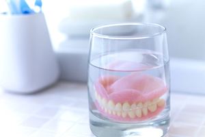 Full dentures in Waterford soaking in glass on bathroom counter