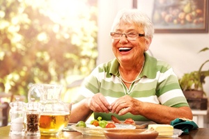 Woman with dentures in Waterford smiling at dinner table